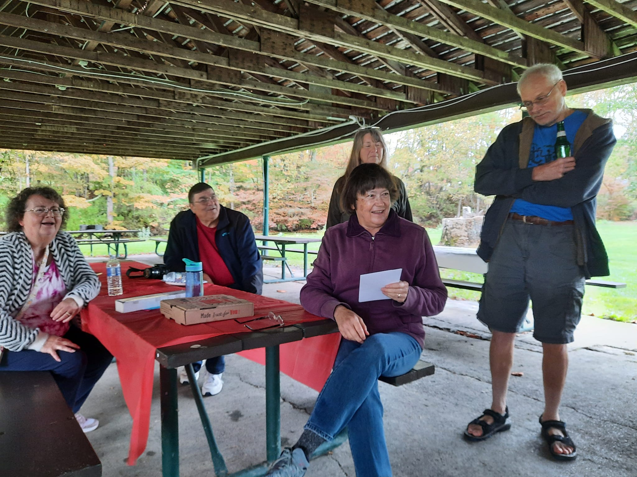 Reading trivia questions at the Trout Ponds 9/29/24 - Pam Andreas Watson, Mike Mauersberg, Carol Knieriem (standing), Julie Thompson Sorcek sitting reading the cards, Ron Sorcek